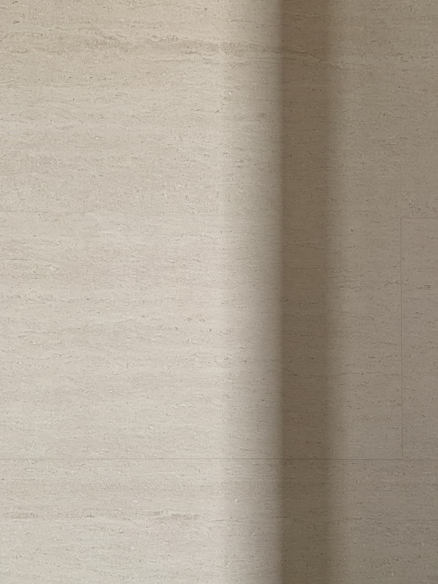 A honed limestone wall with a single vertical joint.